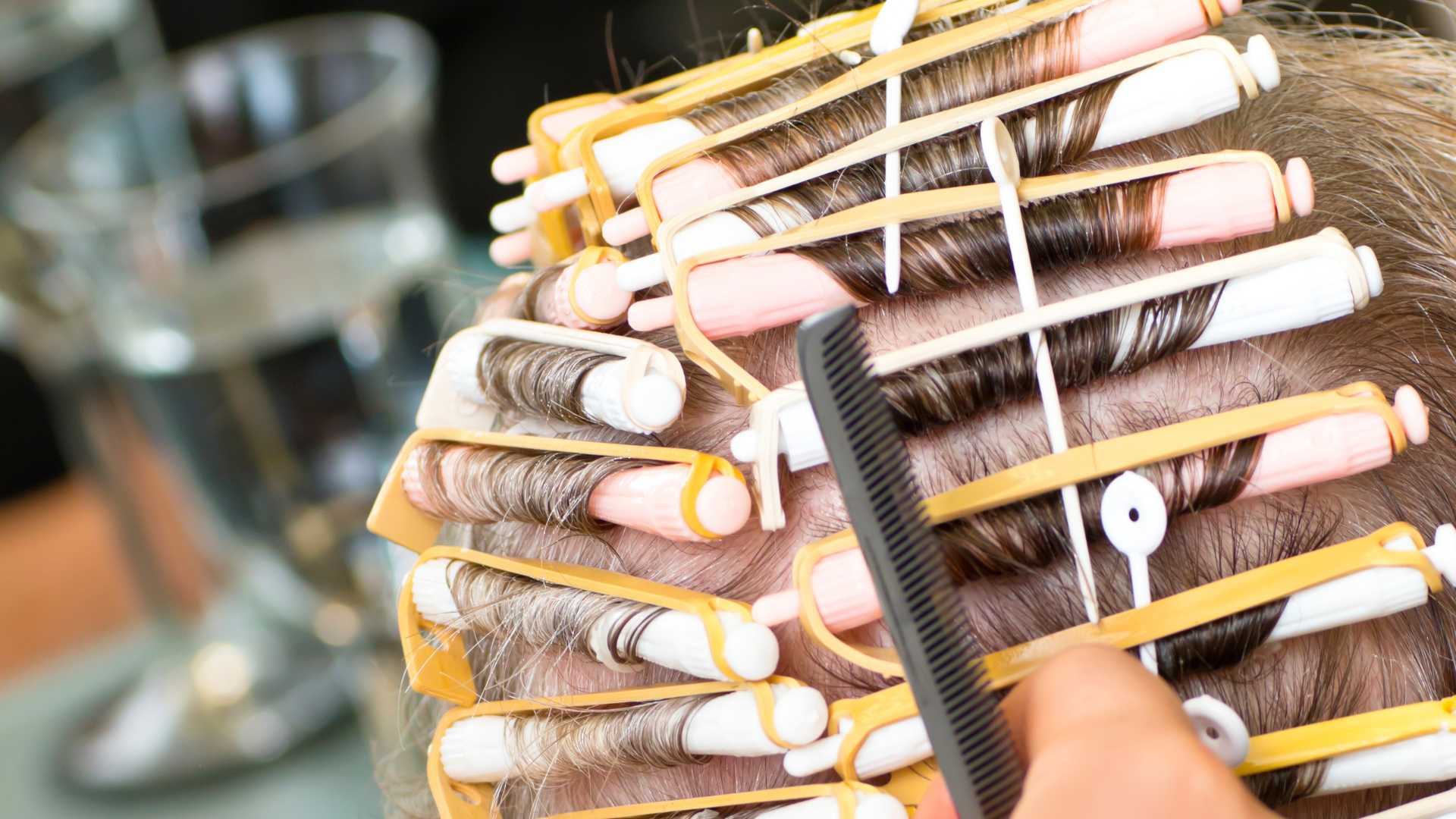 Client with hair wrapped in perm rods for a permanent wave service